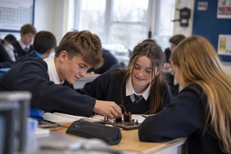 Estudiantes con uniforme montando un circuito en una clase de tecnología de su colegio en Irlanda